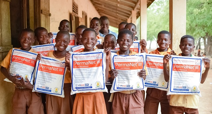 Image of children at a school in Ghana holding malaria nets that were distributed.