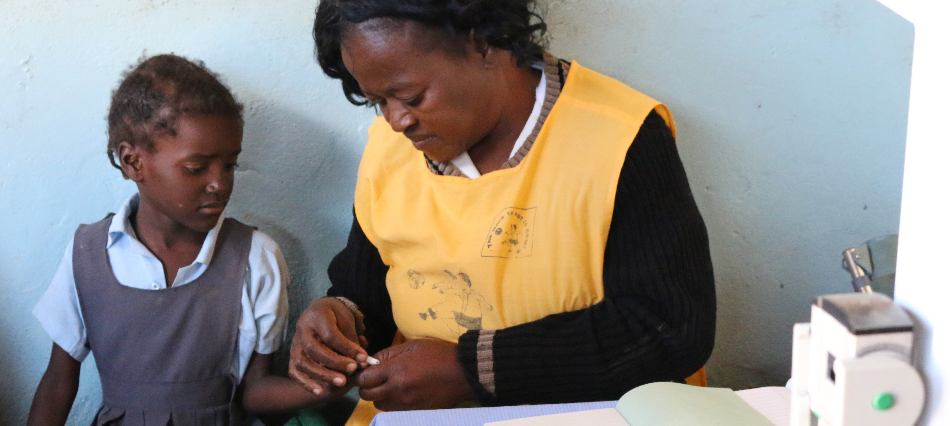 A woman conducts an HIV test on a young girl.