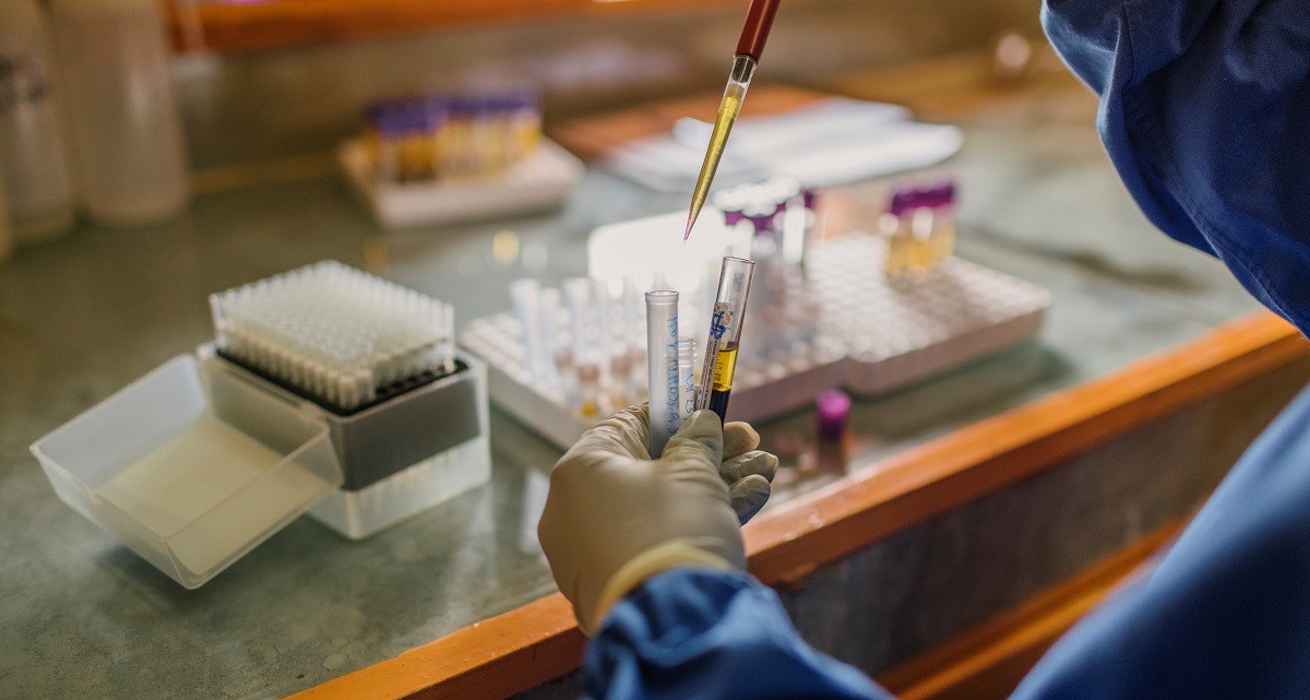 Photo of a lab technician's gloved hands handling lab samples