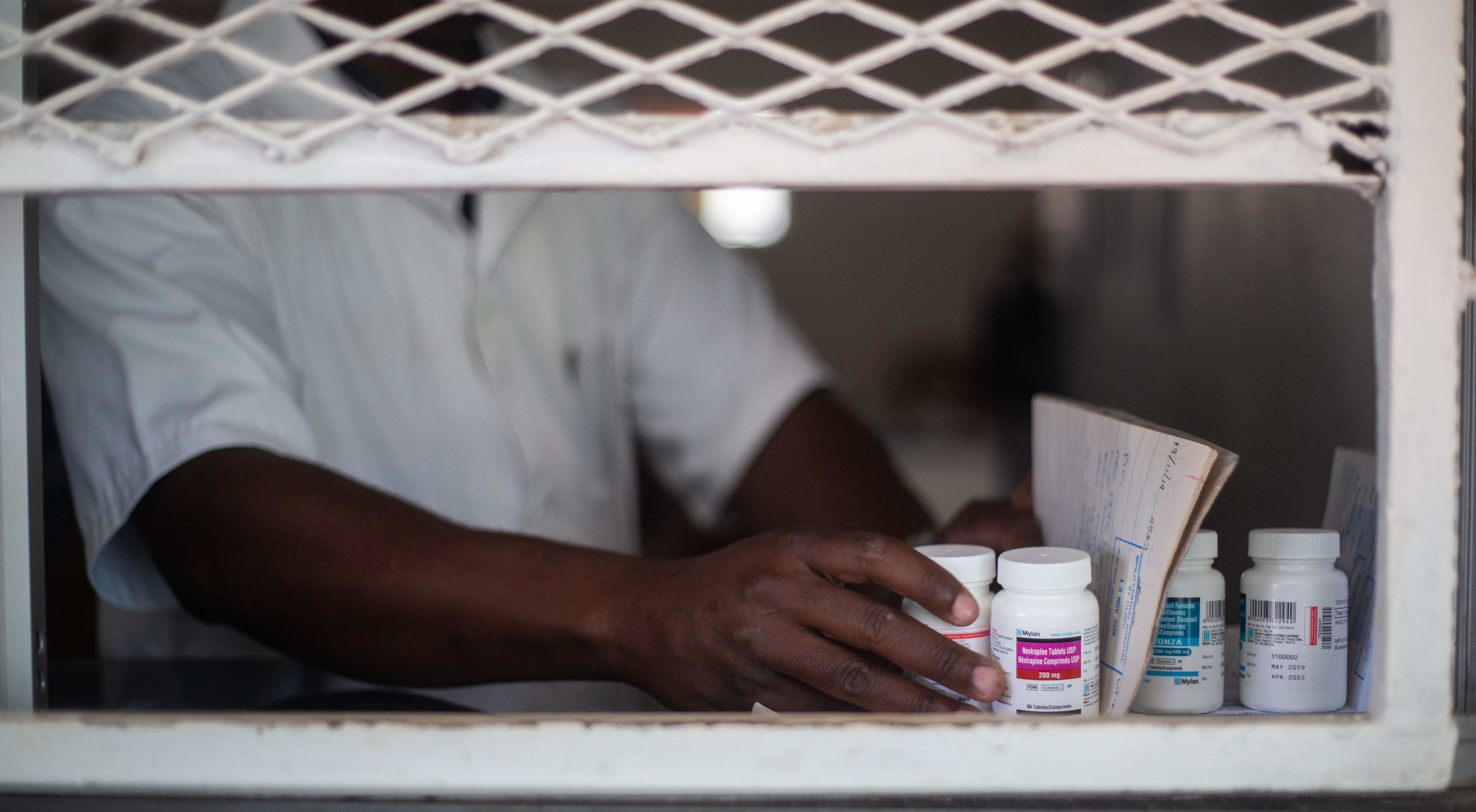 Image of a pharmacist's hand dispensing medicines at a pharmacy in Zimbabwe