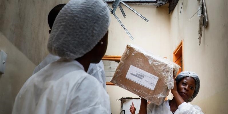 Health center workers in Mozambique moving boxes two days post Cyclone Idai.