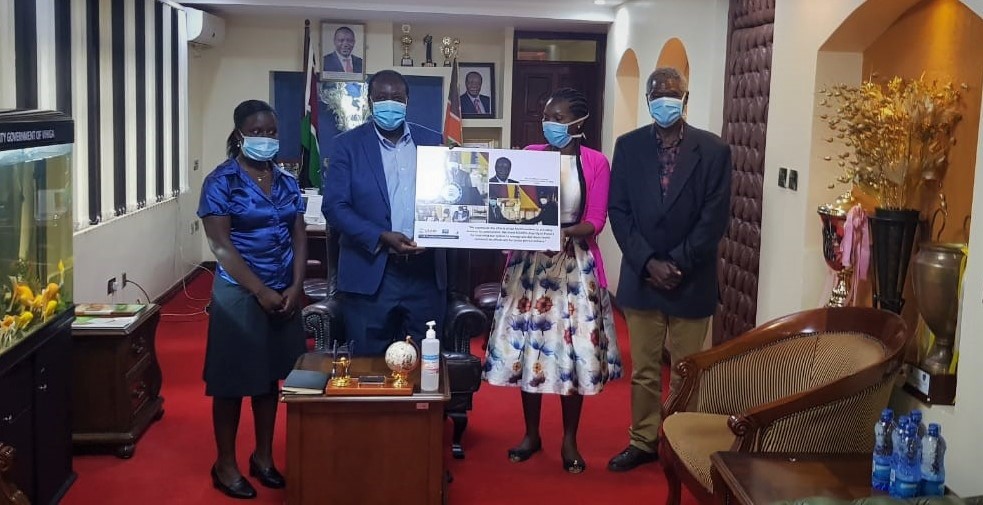 H.E. Governor Ottichillo receives a photo collage that commemorates the award ceremony from Mercy Amadi, Afya Ugavi