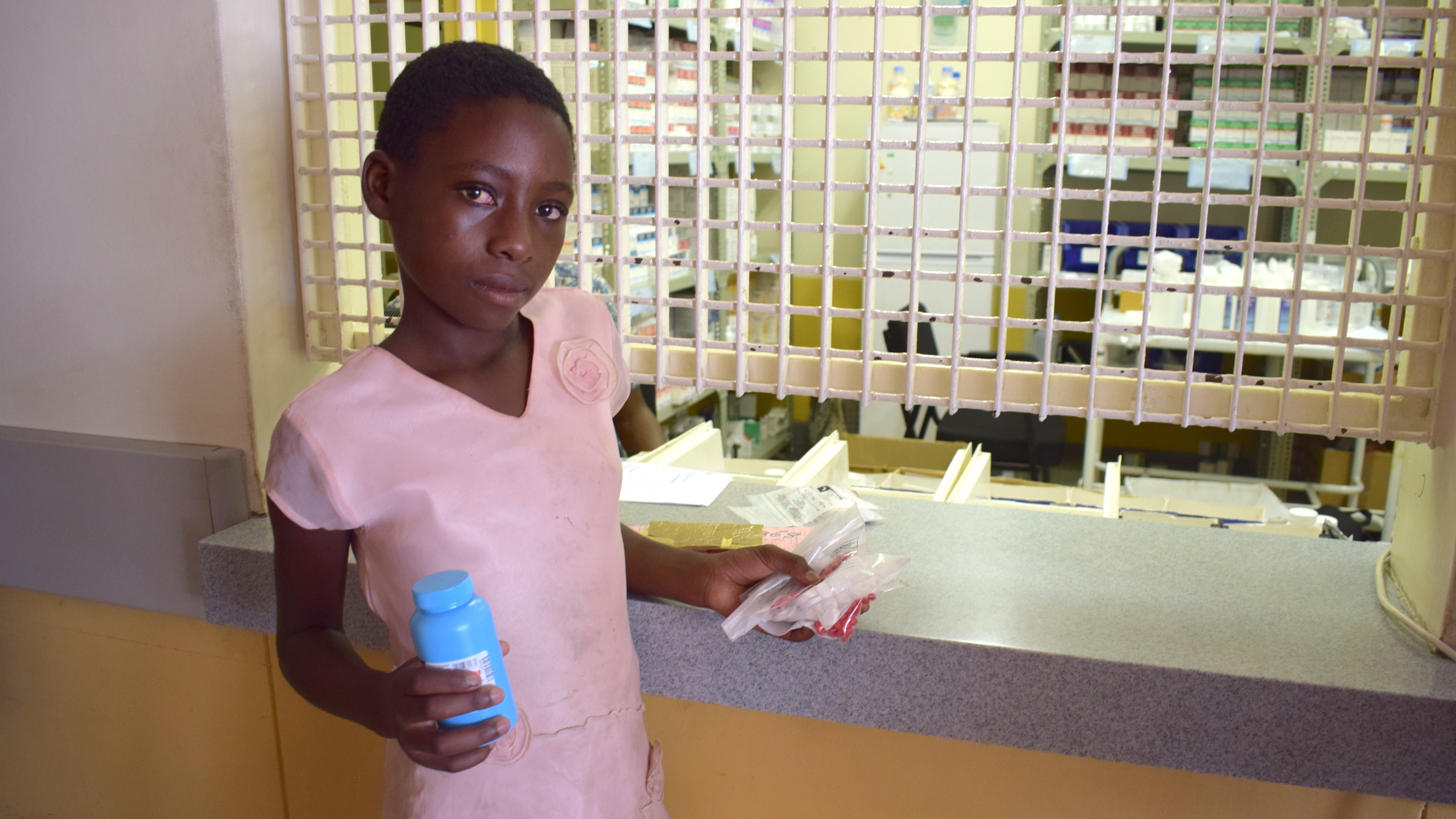Young woman holds multi-month HIV/AIDS medicine at clinic in Namibia