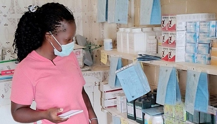 Pharmacist stocking shelf in pharmacy.