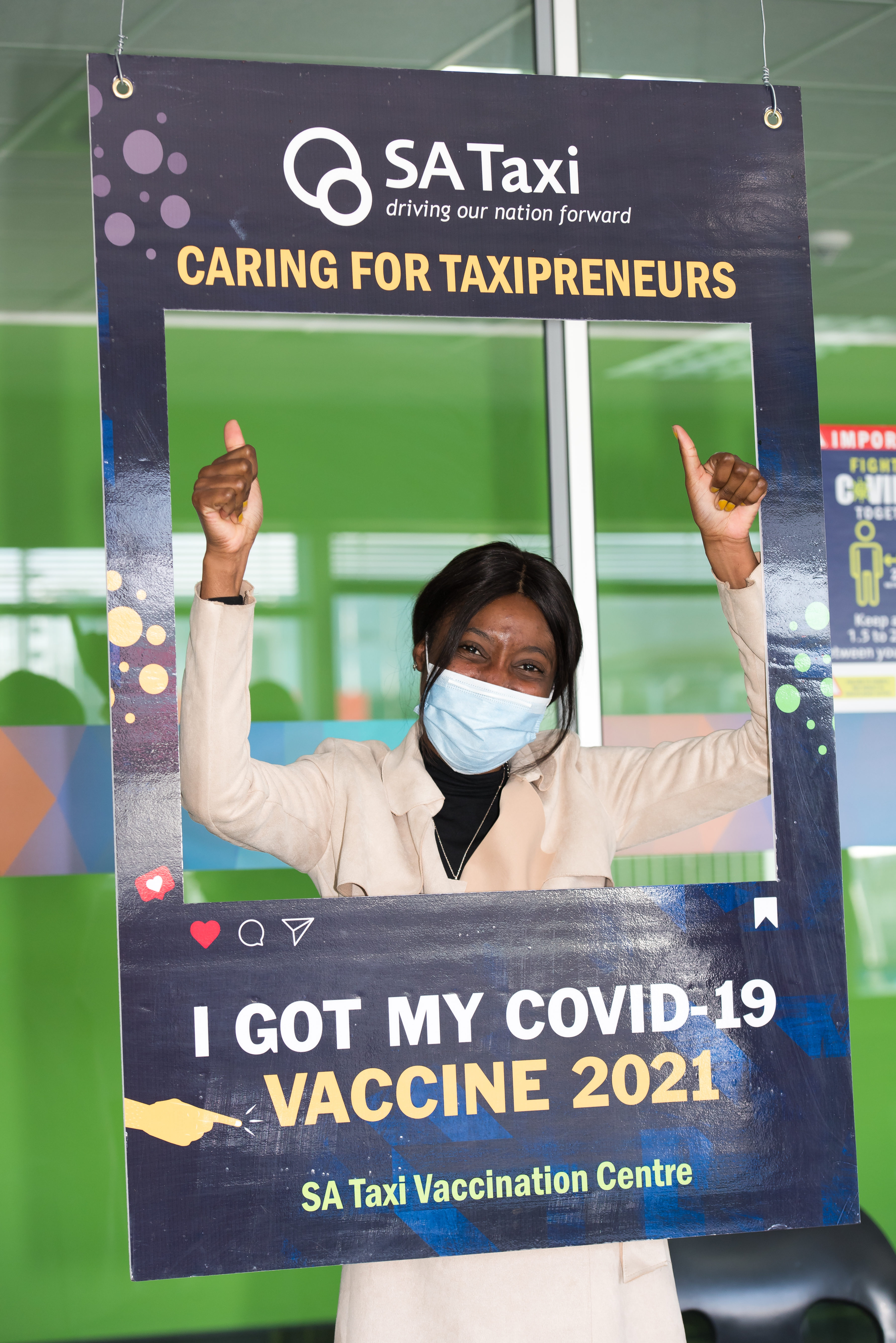 A vacinated woman giving a thumbs up at the SA Taxi Vaccination Site