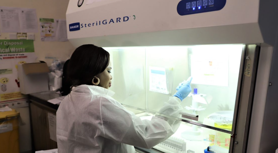 Nigerian lab tech uses equipment under sterilization hood to test biological samples