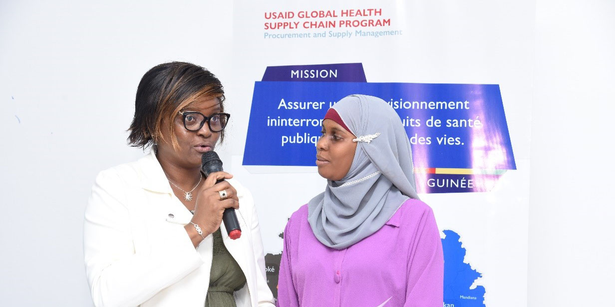 two Guinean women discuss an LMIS technology training with microphones