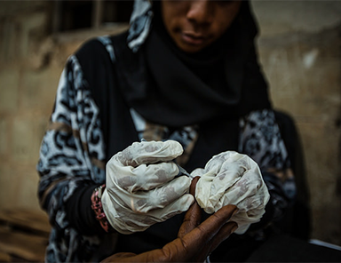 District malaria surveillance officer with gloves tests for malaria.