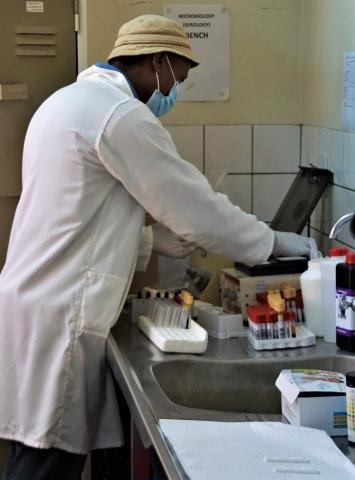 Person in laboratory in Lesotho organizes test tubes containing samples for testing.